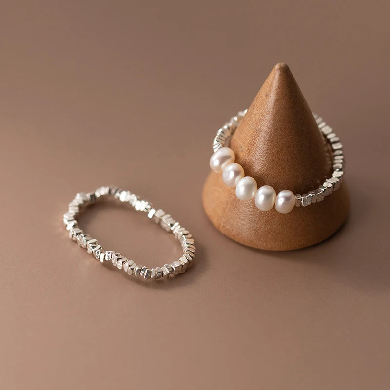 Elegant 925 sterling silver ring with a lustrous pearl centerpiece, set in a sleek geometric band for timeless style.