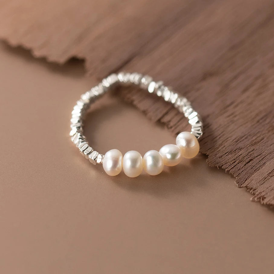 Gleaming 925 sterling silver ring with a lustrous pearl centerpiece, set in a sleek, minimalist geometric band.