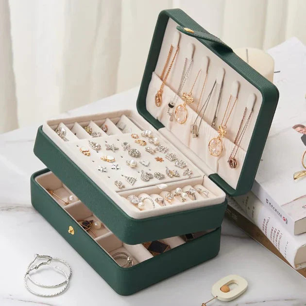Elegant green jewelry box with compartments for rings, earrings, and necklaces, filled with various gold and silver jewelry pieces