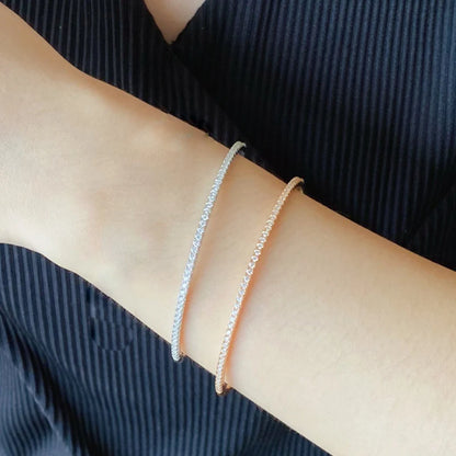 Gleaming gold bangle with a sparkling zircon stone centerpiece, showcasing a minimalist, unisex 6cm round design.