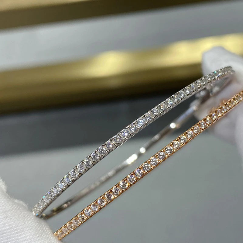 Gleaming gold bangle with a sparkling zircon stone centerpiece, showcasing a minimalist, unisex round design.