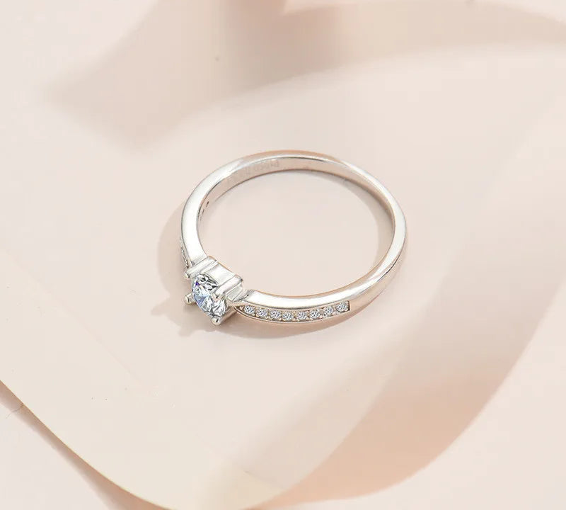 Elegant 925 sterling silver bridal ring set featuring a sparkling 5mm round brilliant moissanite in a classic 4-prong solitaire setting.