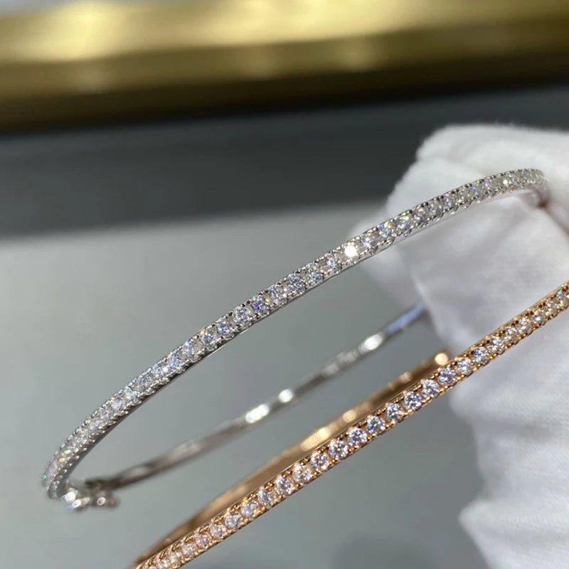 Gleaming gold bangle with a sparkling zircon stone centerpiece, showcasing a minimalist, unisex round design.
